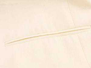 Macro detail of high-quality stitching and welt pocket on cream longline blazer