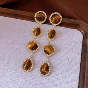 Detailed macro view of vintage long gold drop earrings with amber stones and rhinestones