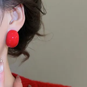 Elegant red acrylic teardrop stud earrings worn by a model for a stylish modern look