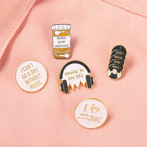 Detail of five music-themed enamel pins featuring vinyl records and headsets on denim