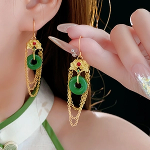 Detail of gold-plated lute lotus earrings featuring green jade rings and long chain tassels