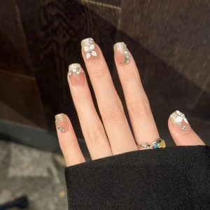 Handmade press-on nails with 3D white flowers, pearls, and gold glitter gradient