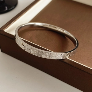 Macro detail of silver bangle featuring engraved Mahjong characters and textured pattern