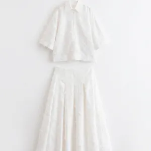 Élégant ensemble deux pièces blanc avec chemise à franges et jupe midi plissée