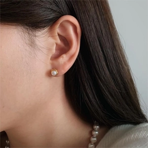 Elegant 925 sterling silver pearl stud earrings worn by a model in a side view