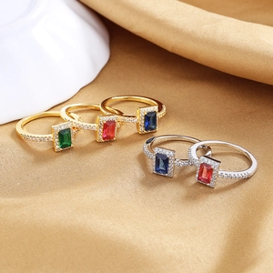 Close-up of luxury gold and silver rings with rectangular colorful zircons and micro-pave