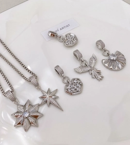 Detail of silver octagonal star, heart and angel wing pendants with white zircon inlays