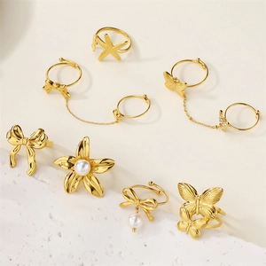 Detailed view of 18k gold butterfly and flower rings with pearls on stone background