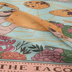 Close-up of woven fabric texture with colorful zodiac signs and taco illustration