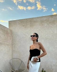 Détail d'une jupe longue blanche élégante à taille haute avec pochette tissée et haut noir