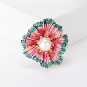 Macro detail of enamel flower brooch with white pearl center and glitter petals