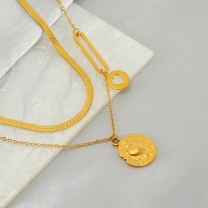 Double-layered gold necklace with snake chain and heart coin pendants on marble