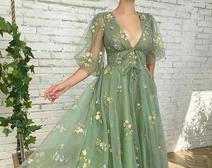 Detail of floral embroidery on a sage green tulle dress with puffy sheer sleeves