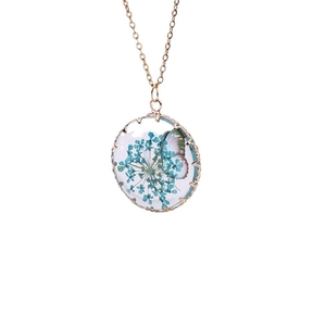 Bohemian gold necklace featuring a round glass pendant with dried blue flowers and butterfly