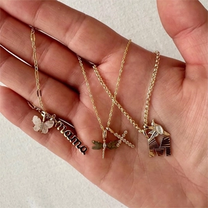 Detailed close-up of golden necklaces featuring butterfly, dragonfly, and cross charms