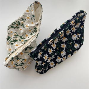 Close-up of intricate daisy embroidery on durable canvas cosmetic bags in beige and black