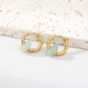 Detail of gold hoop earrings with light green translucent natural stone beads on stone