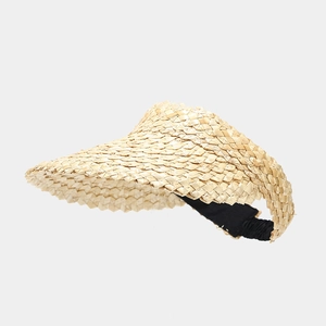 Close-up of handwoven straw sun visor with wide brim and black elastic back strap