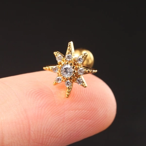 Gold eight-point star cartilage piercing stud with micro-paved zircons on a fingertip
