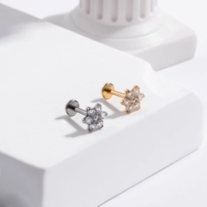 Macro detail of G23 titanium floral cartilage studs with zircon in gold and silver