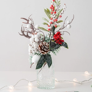 Christmas pine cone and red berry floral arrangement with deer antlers in a glass vase