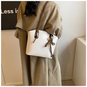 Détail d'un sac cabas bicolore avec pendentif raquette de tennis et logo doré chic