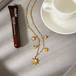 Collier céleste doré avec pendentifs soleil lune et étoiles sur fond en velours gris