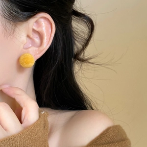 Macro side view of model wearing a bright yellow flocked round stud earring for daily wear