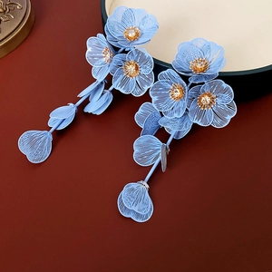 Détail de boucles d'oreilles fleurs bleu clair avec pistils dorés et cristaux