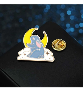 Macro shot of blue bunny on white cloud with yellow moon enamel pin on gold base