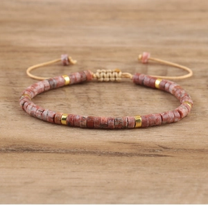 Close-up of adjustable imperial stone woven bracelet with golden spacer beads on wood