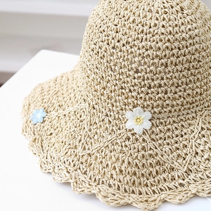 Handmade beige straw sun hat with large wavy brim and delicate daisy floral accents