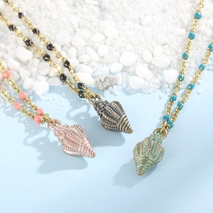 Macro shot of seashell pendant necklace with colorful beads on a beach sand background