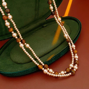 Vue détaillée d'un collier multicouche en œil de tigre et perles dans un écrin vert