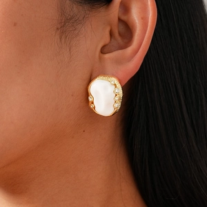 Detail of oval acrylic earring with gold textured frame and crystal accents on ear