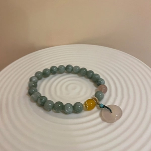 Detail of beaded chalcedony bracelet with green beads and pink peace buckle charm