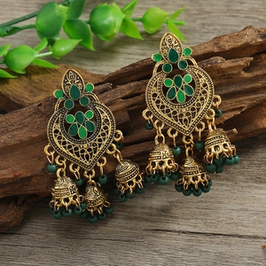 Bohemian gold tassel earrings with green gemstones and bells on rustic wood background