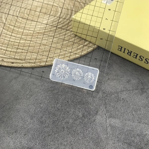 Macro view of transparent silicone mold with daisy patterns beside a ruler for scale