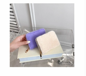 Nahaufnahme von flauschigen Kunstpelz-Geldbörsen in Lila und Creme mit Goldreißverschluss