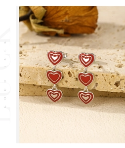 Macro detail of S925 sterling silver long drop earrings with red enamel hearts