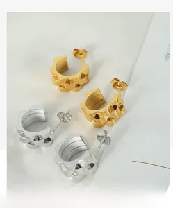 Detail view of gold and silver scalloped C-shape stud earrings with polished finish