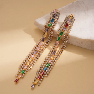 Macro detail of long tassel earrings with multicolored rectangle zircons and gold base