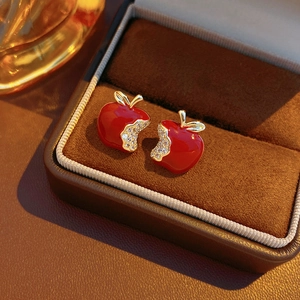 Close-up of luxury red apple stud earrings with gold plating and sparkling zircon inlay