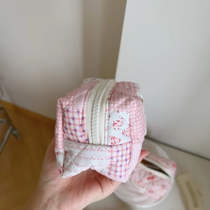 Close-up of pink floral quilted pouch with zipper detail and soft fabric texture