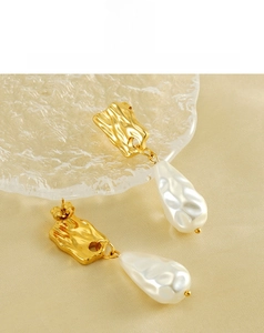 Détail de boucles d'oreilles perles d'eau irrégulières avec texture dorée sur soie