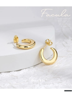 Detailed macro view of gold-plated C-shaped chunky hoop earrings with high-polish finish