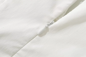 Macro shot of the white invisible zipper closure and fine fabric texture on the V-neck dress