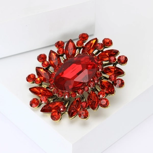 Vintage floral brooch with large red crystal and gold alloy base on white display