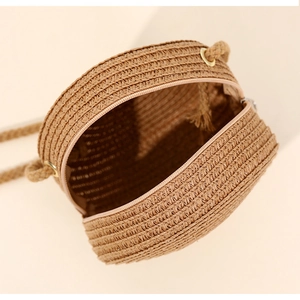 Detail view showing the metal zipper and interior space of a round straw crossbody bag