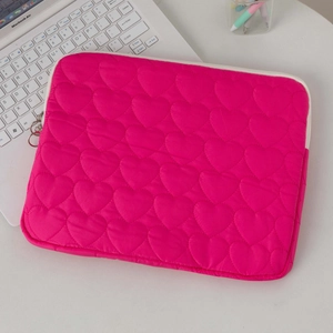 Detail of rose red quilted heart laptop sleeve with metal zipper on a white desk